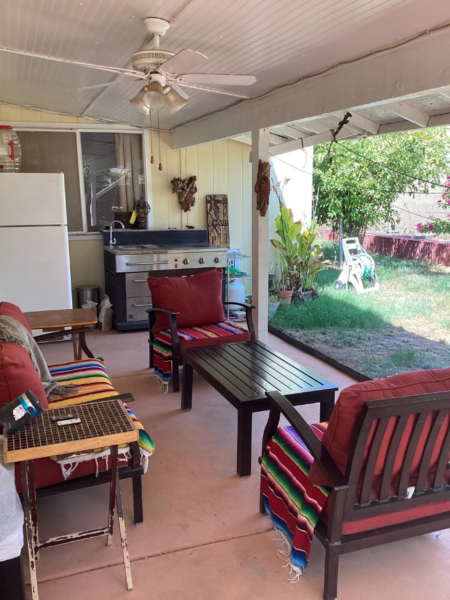 The covered patio, with seating and blankets, looking out to the garden